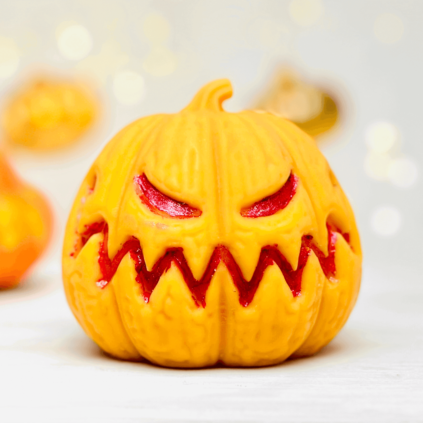 Spooky Jack-O-Lantern silicone candle mold in vibrant orange with red accents for Halloween decor.