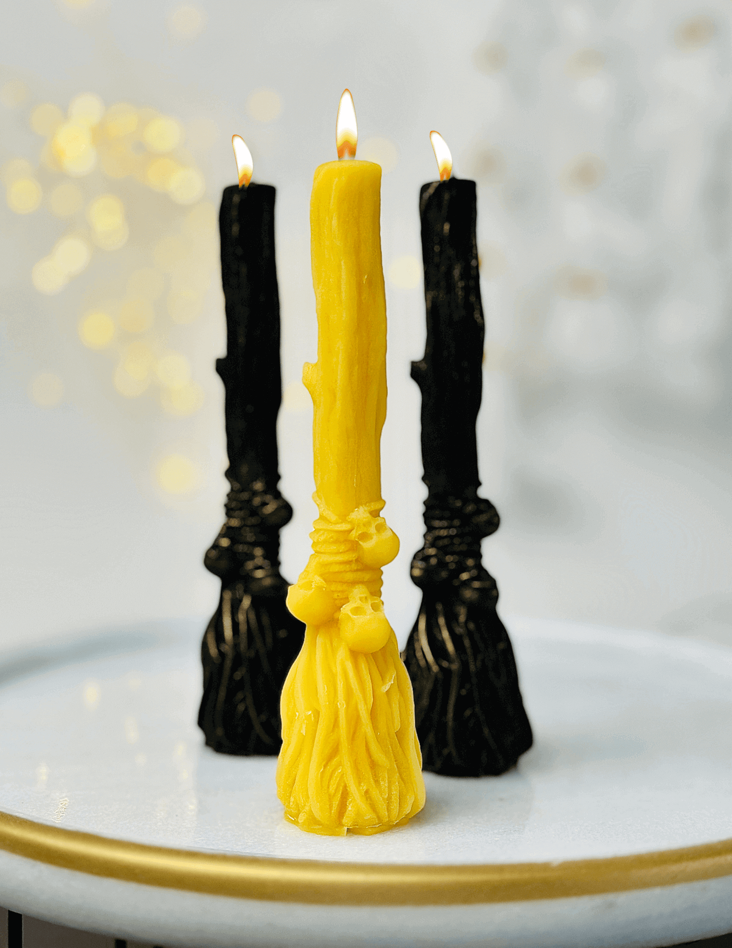 Witchcraft-inspired candles on a tray, featuring a yellow broom candle and black skull candles, ideal for Halloween.