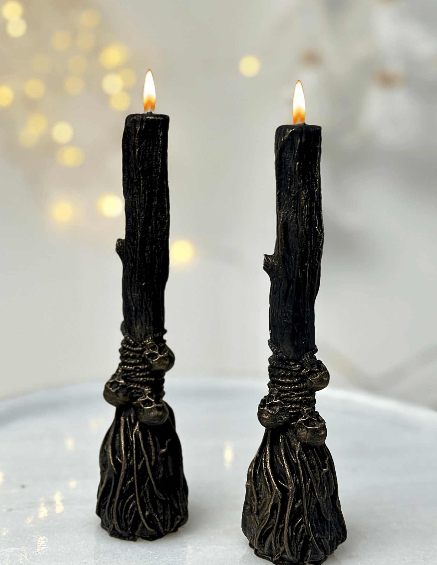 Two black witchcraft candles styled like tree branches on a light surface, adding a mystical touch for Halloween.