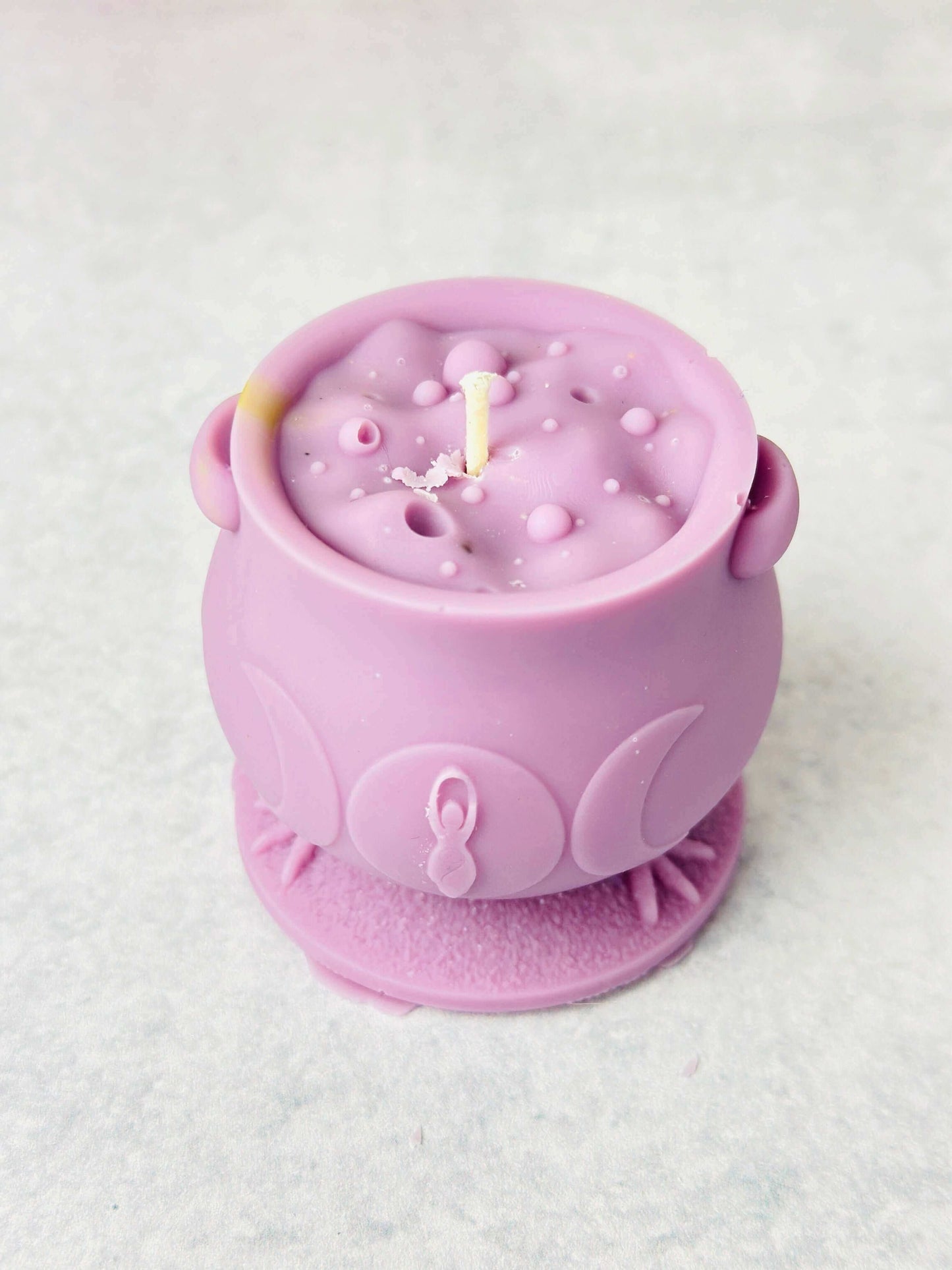 Unique purple witchcraft cauldron-shaped silicone candle mold with a white wick.