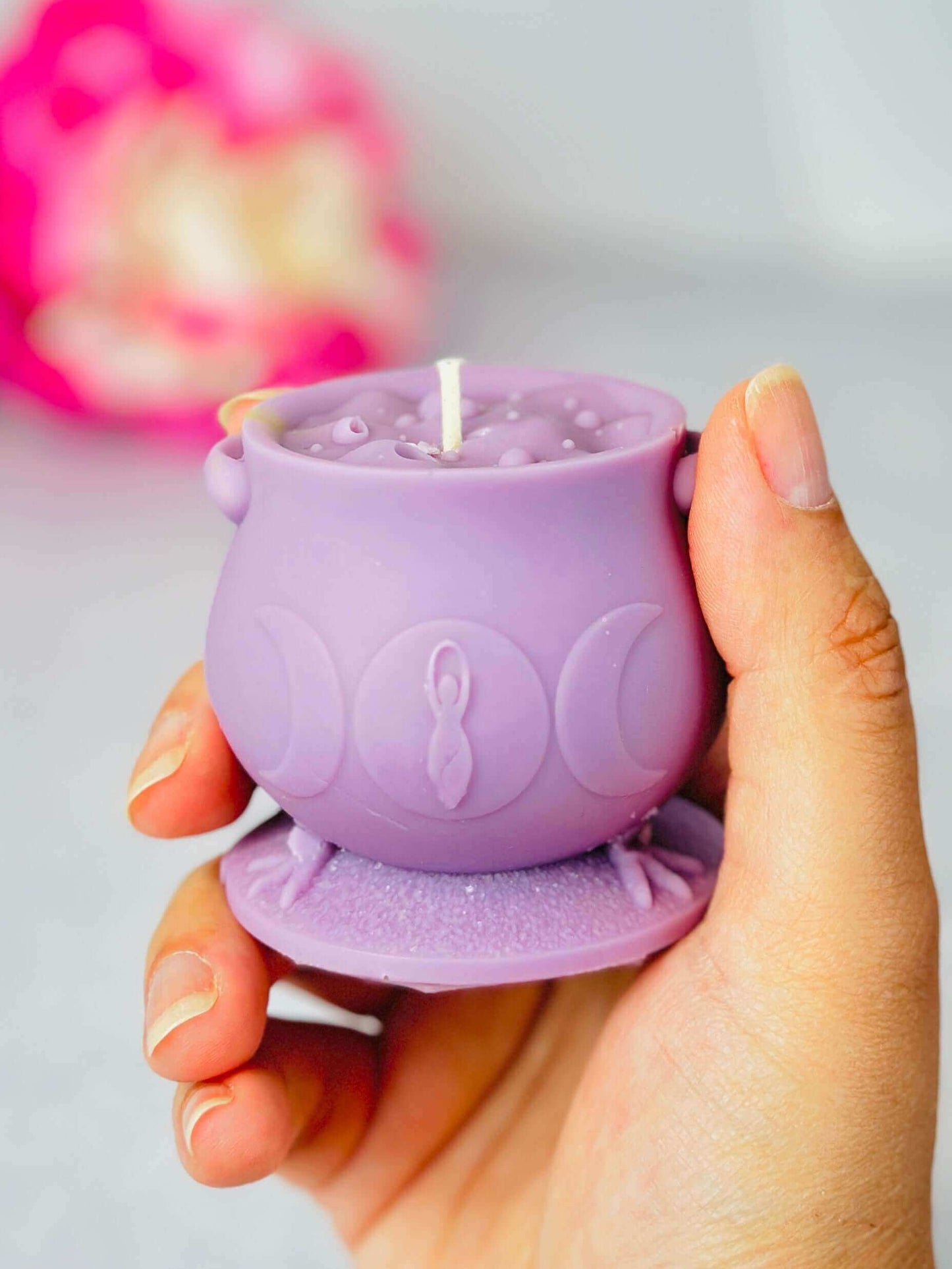 Hand holding a purple witchcraft cauldron candle, showcasing unique silicone mold design by CurlyCandle.