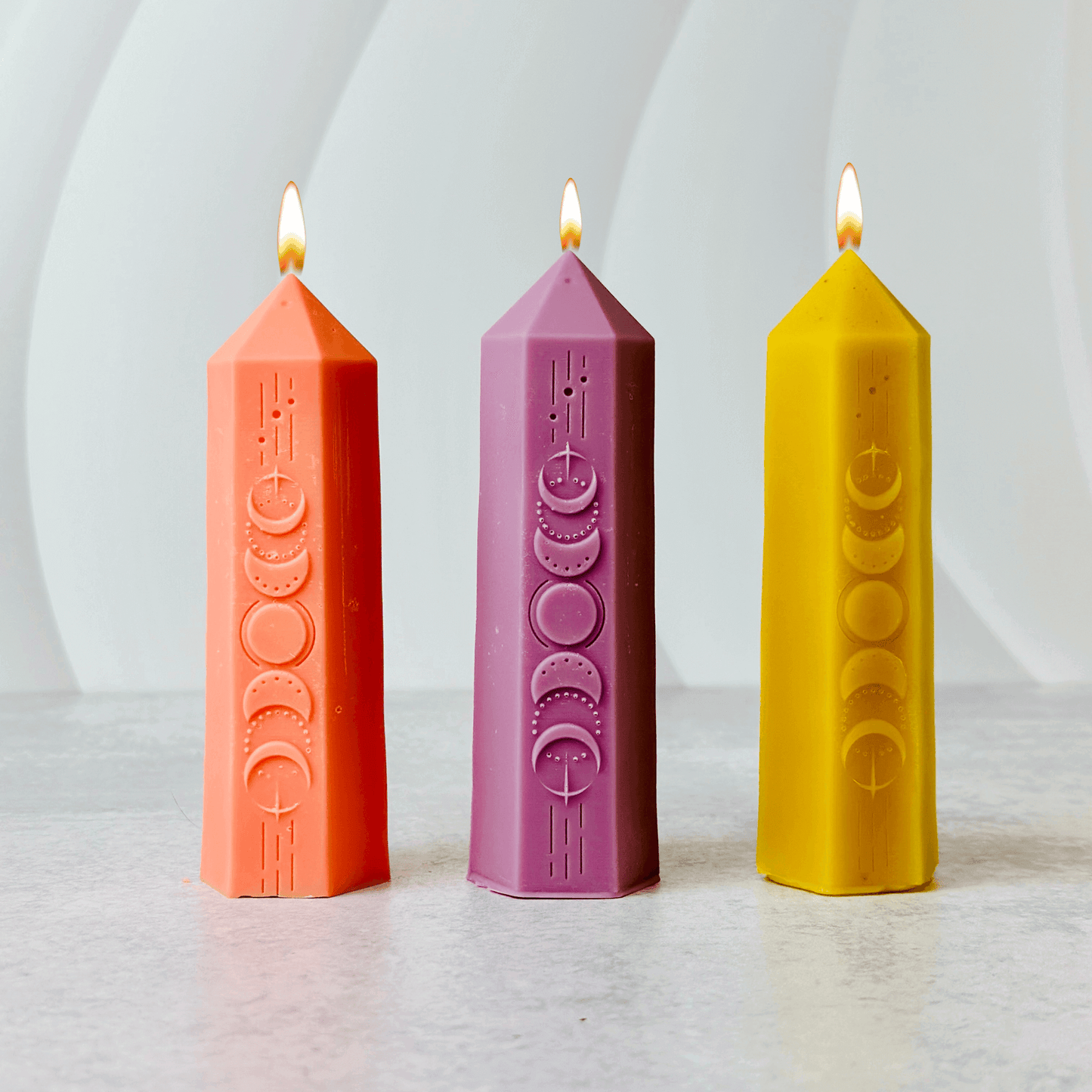 Burning candles in vibrant colors representing moon phases, ideal for Wicca and witchcraft rituals.