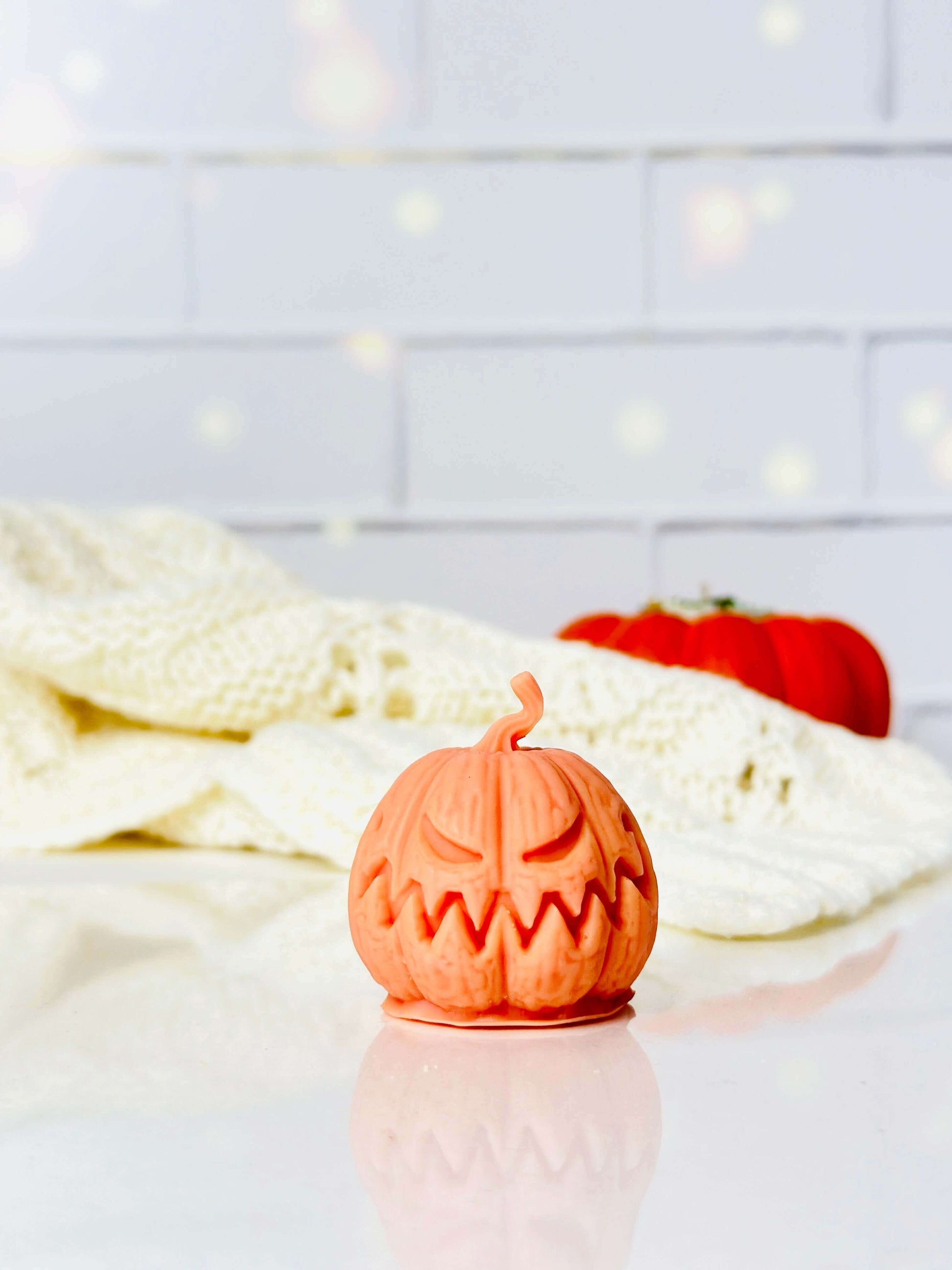 Spooky Jack-O-Lantern silicone candle on a table with a cozy blanket, perfect for Halloween decor.