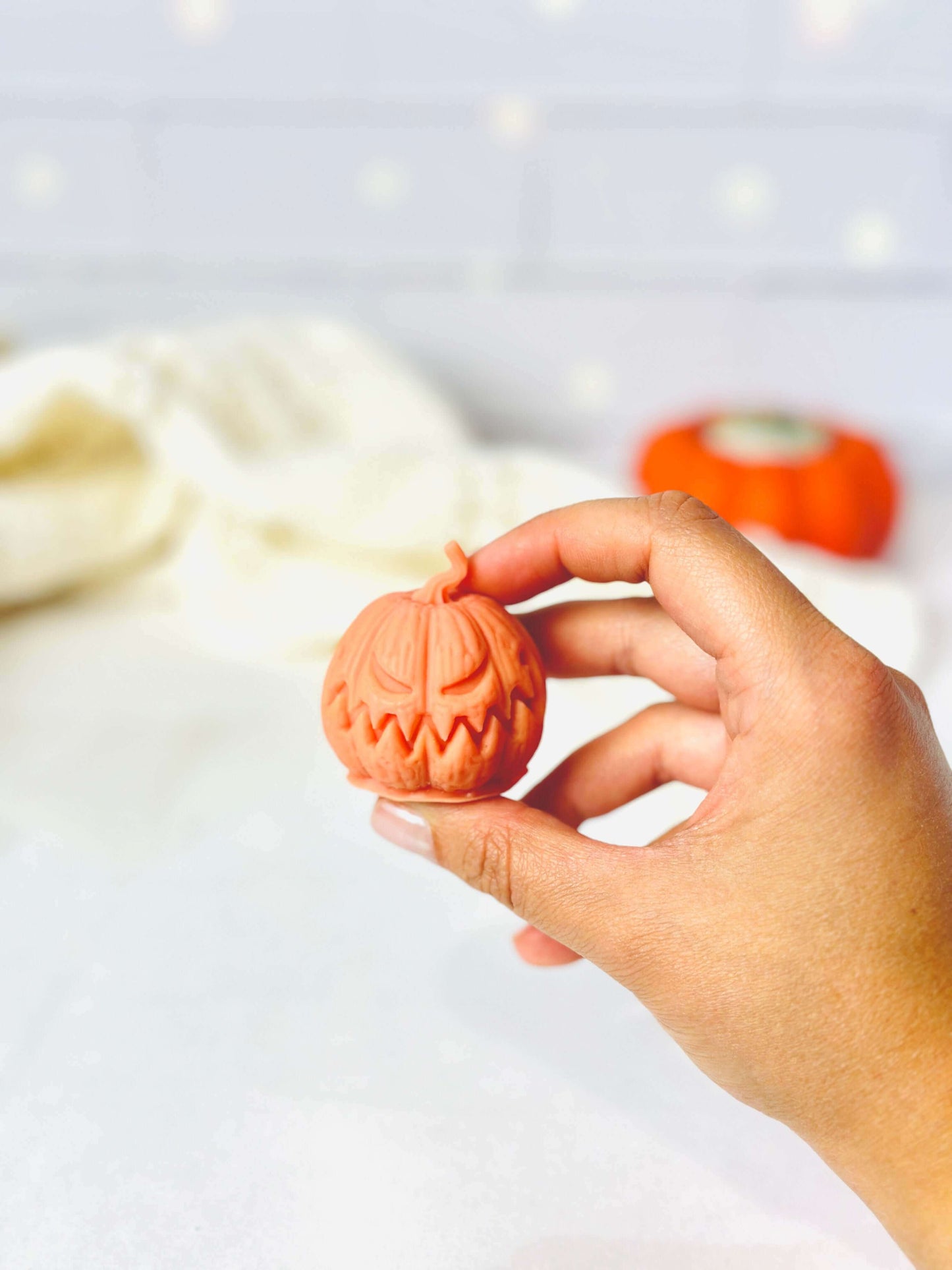 Person holding a spooky Jack-O-Lantern candle made with a silicone mold for Halloween decorations.