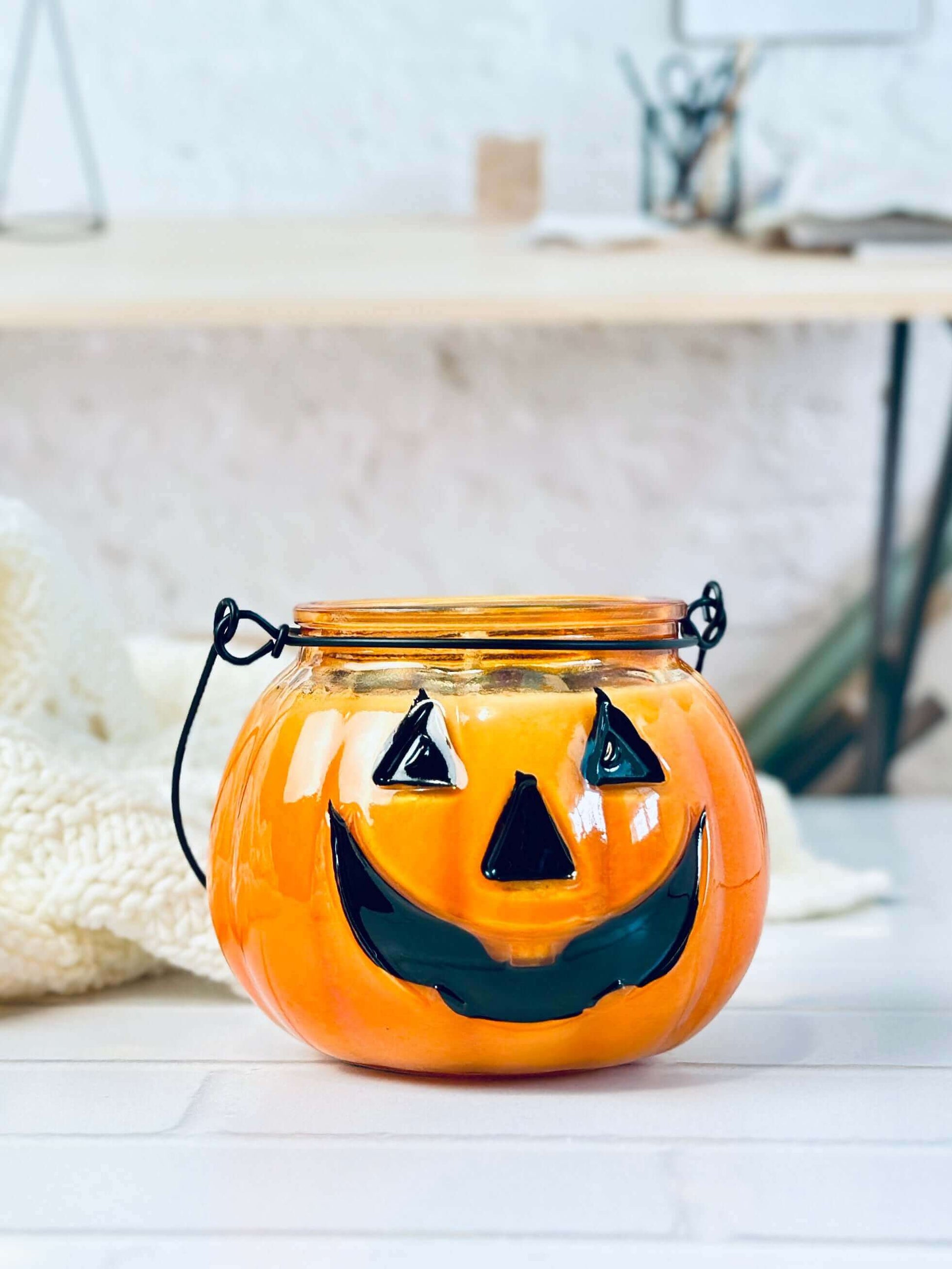 Jack O Lantern pumpkin jar candle with smiling face, perfect for Halloween decor and cozy ambiance.