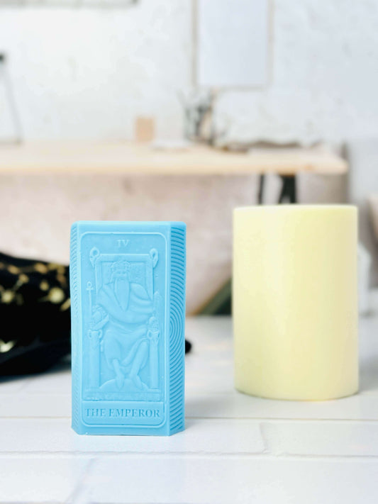 Blue silicone mold of the Emperor tarot card next to a yellow candle in a serene crafting setting.