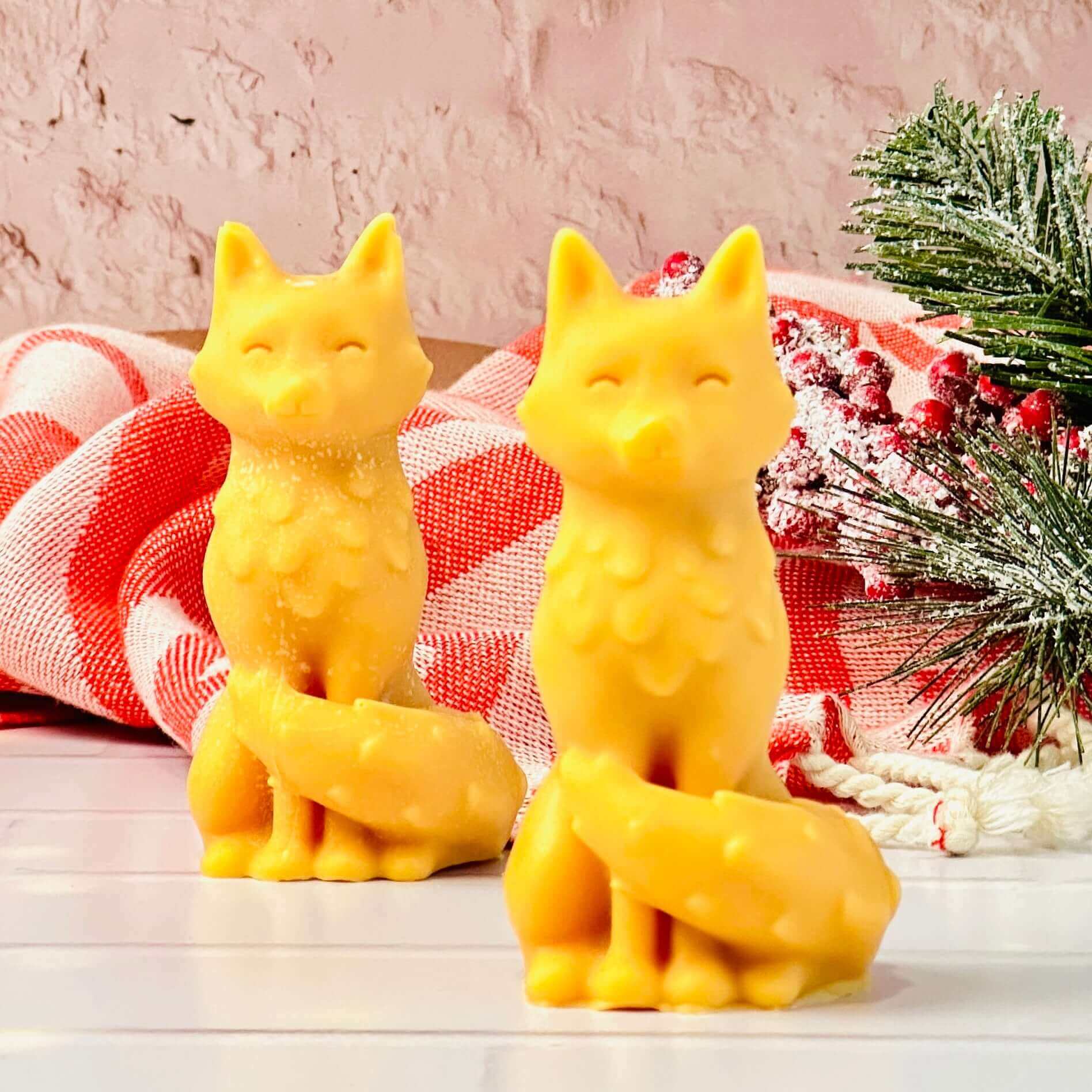 Two yellow fox-shaped candles made with silicone mold, decorated with festive backdrop.