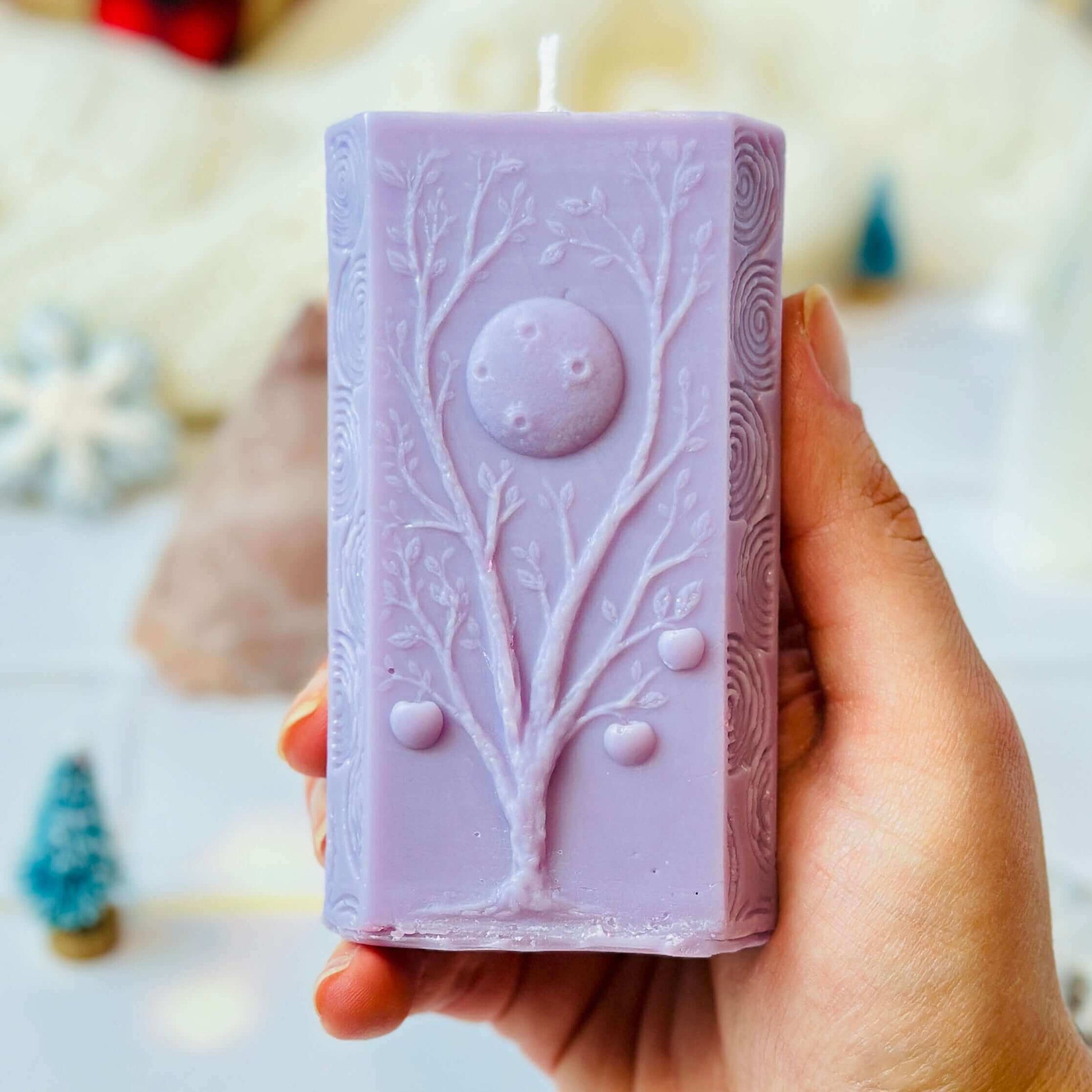 Hand holding a lavender Moon Phases soy candle with tree and moon design, part of the spiritual gift set.