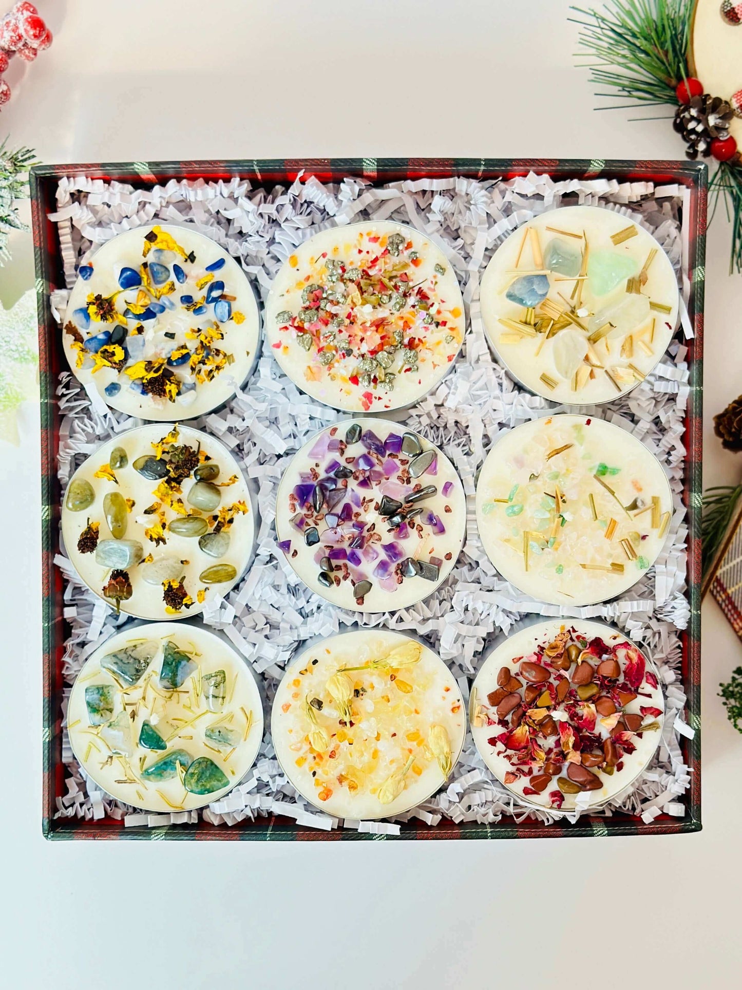 Scented tealight candles set in a gift box featuring various colorful herb and crystal decorations for holiday ambiance.