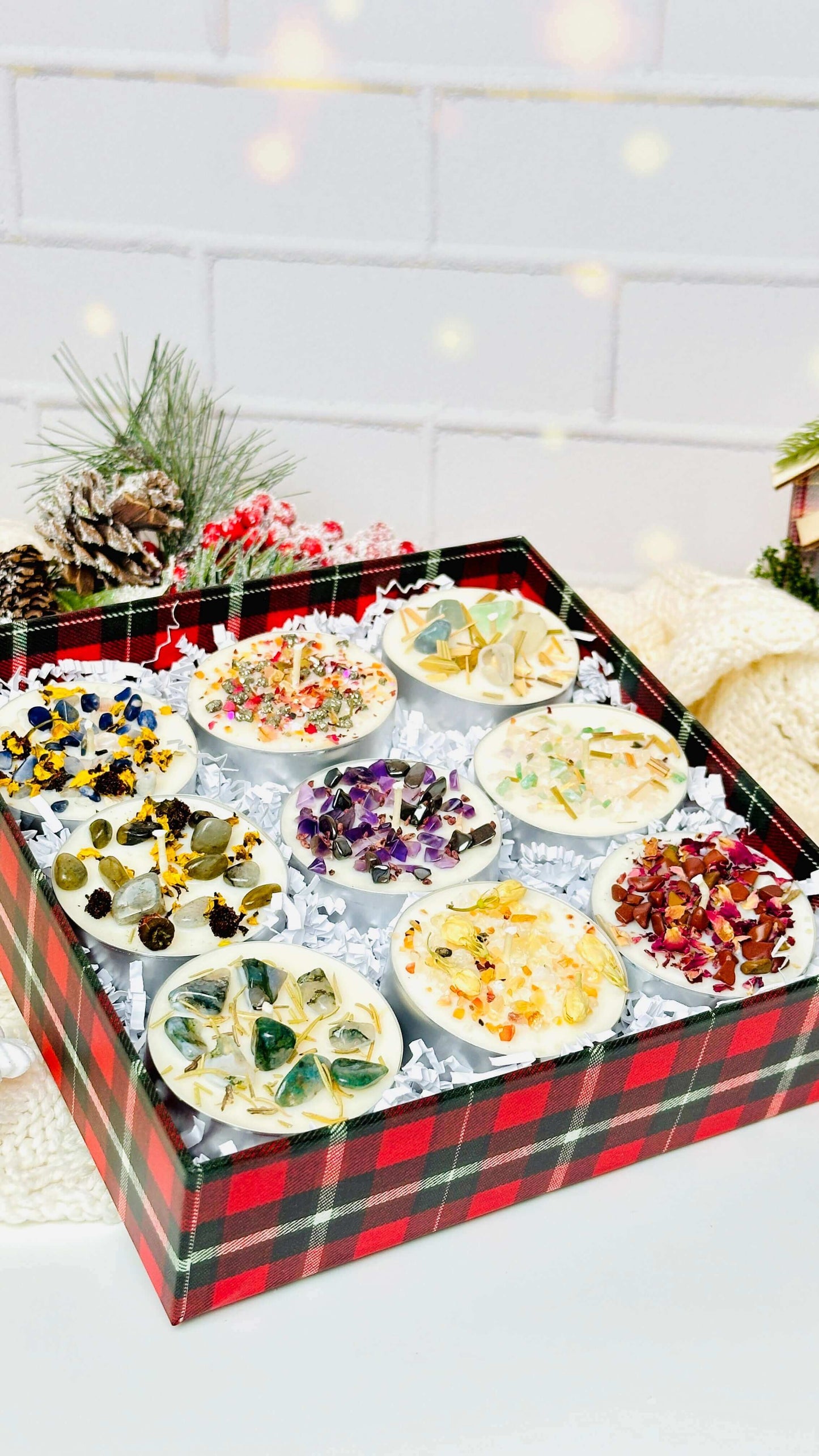 A beautifully arranged set of 9 scented tealight candles with various herbs and crystals in a festive gift box.