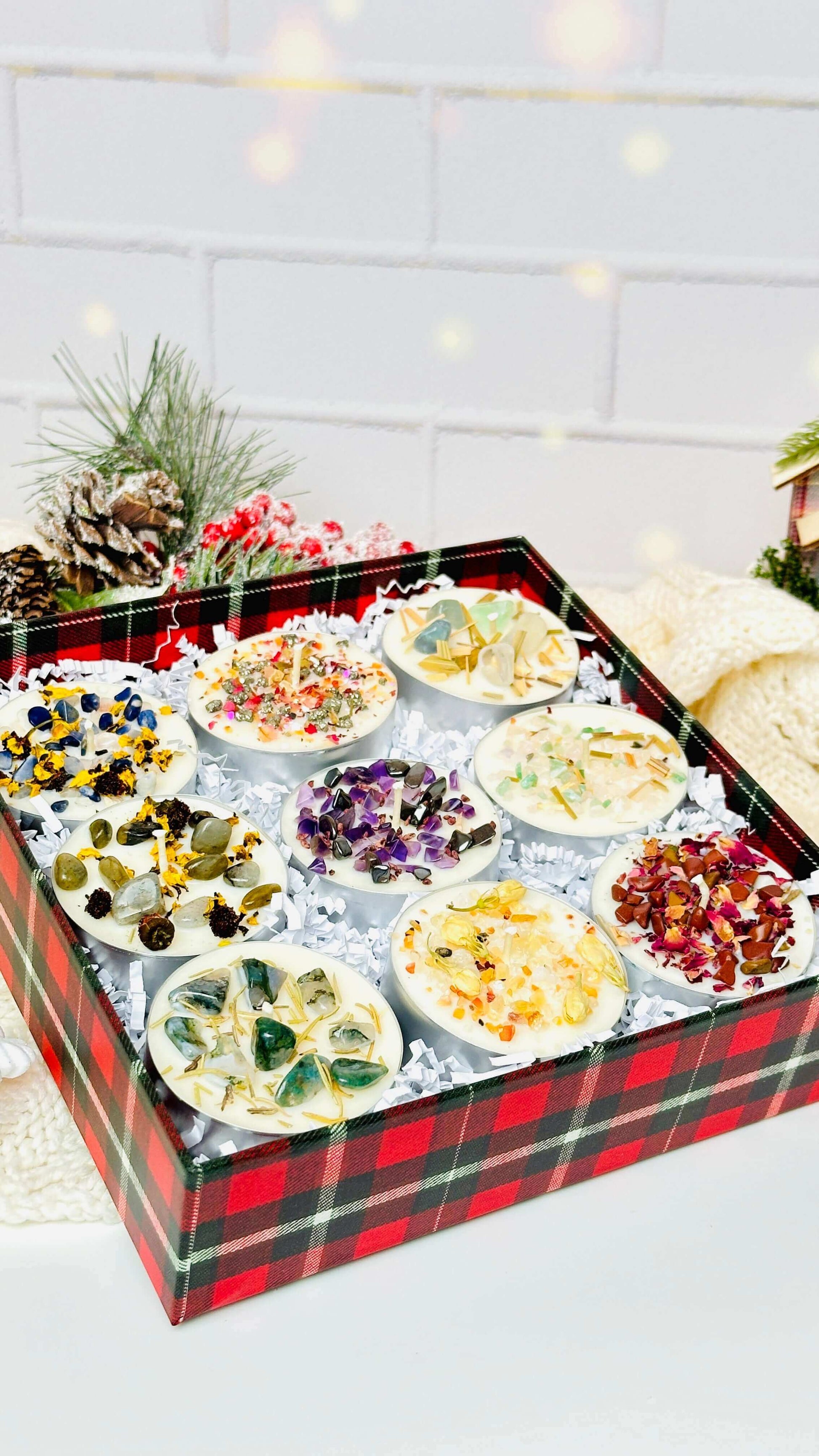 A beautifully arranged set of 9 scented tealight candles with various herbs and crystals in a festive gift box.