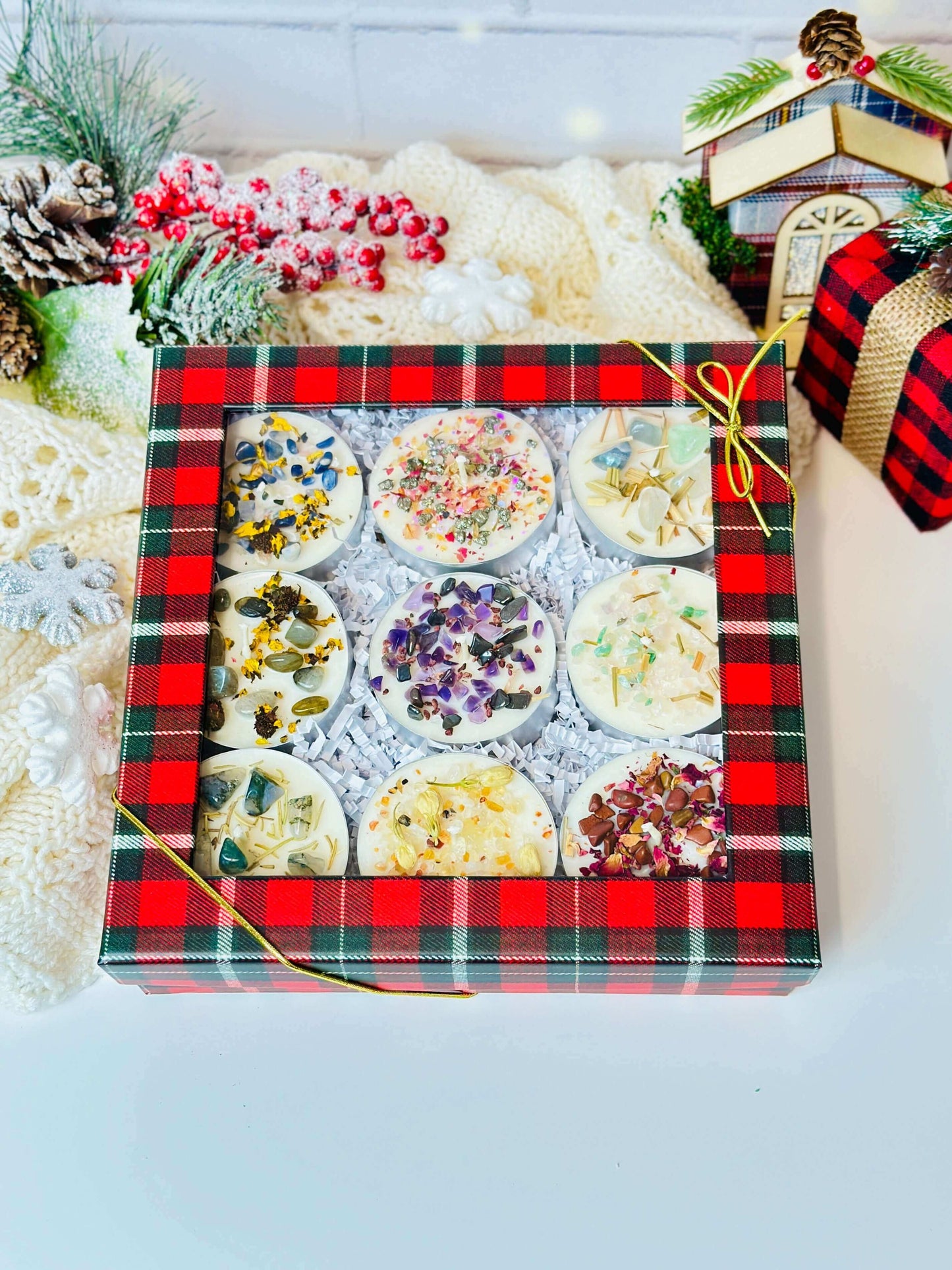 Festively packaged scented tealight candles set with floral decorations in a plaid gift box.