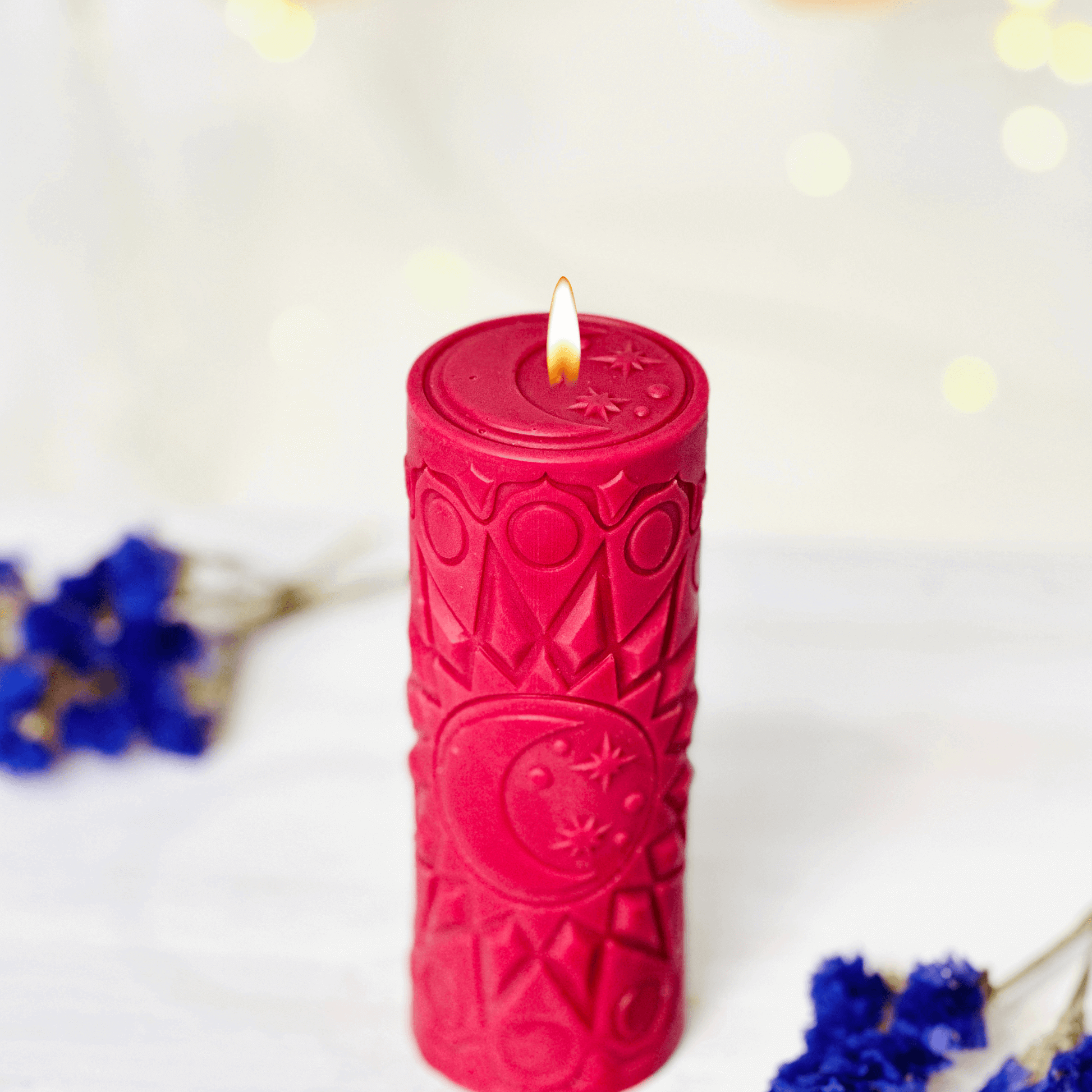 Red spiritual candle with moon and star design, glowing with a flame, ideal for rituals and art creation.