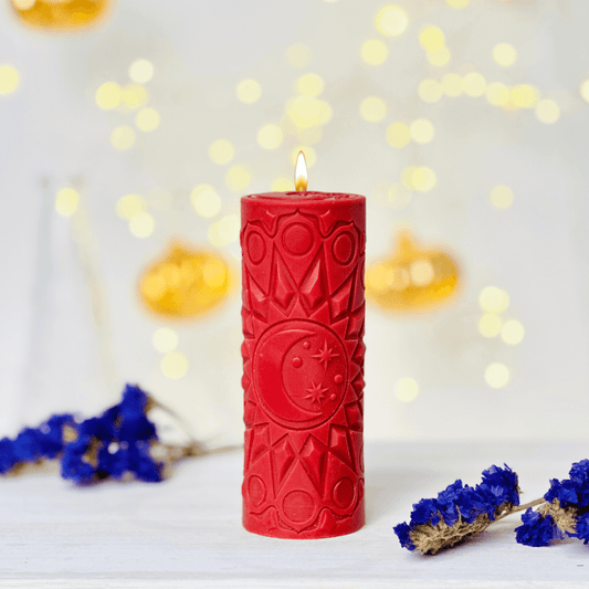 Red spiritual candle with moon design, surrounded by blue flowers and warm lights, perfect for creating a serene atmosphere.