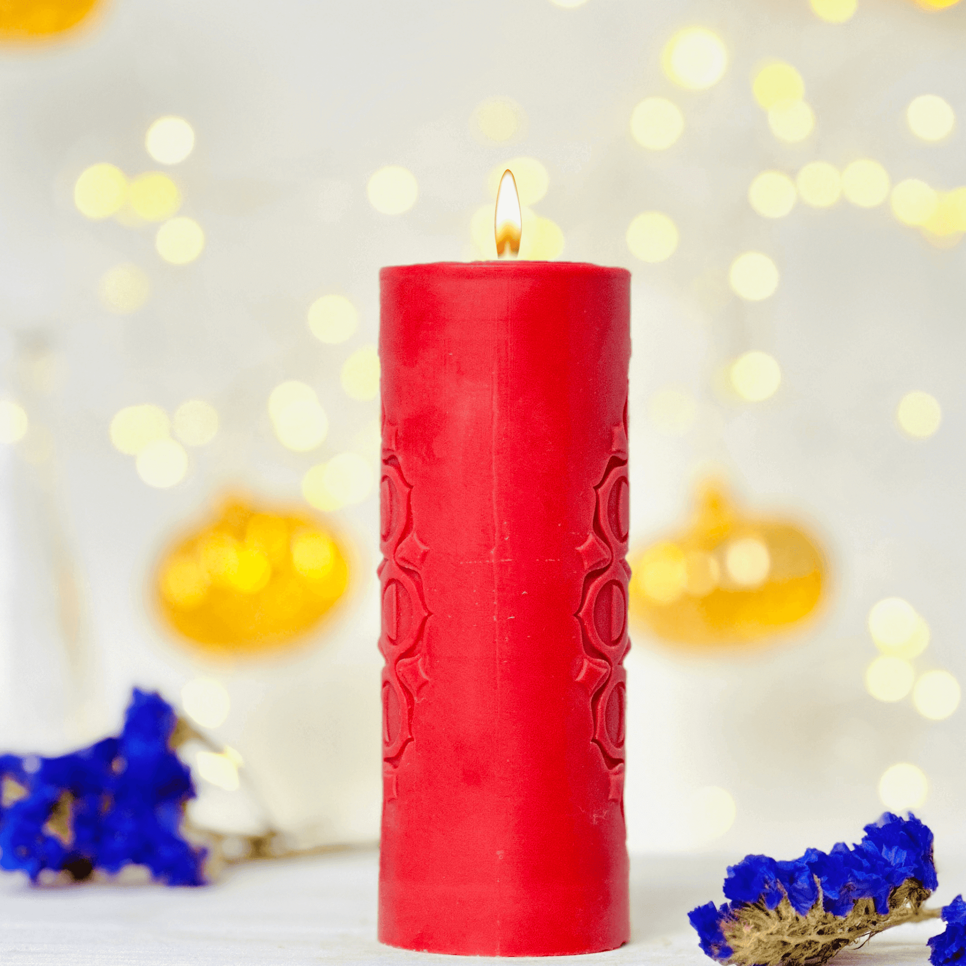 Red candle with flame surrounded by colorful flowers and warm bokeh lights, creating a cozy ambiance.