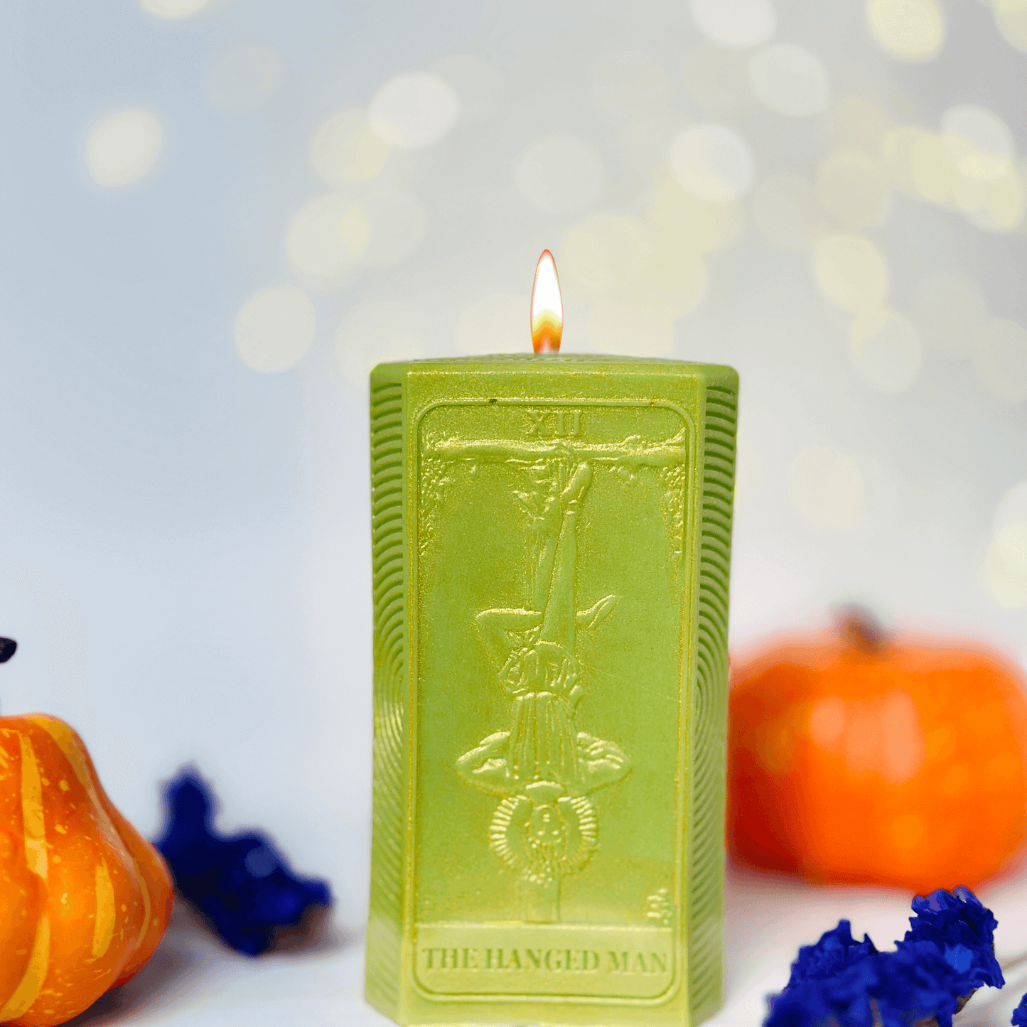 Hanged Man tarot card candle mold displayed with autumn decorations and glowing candlelight.