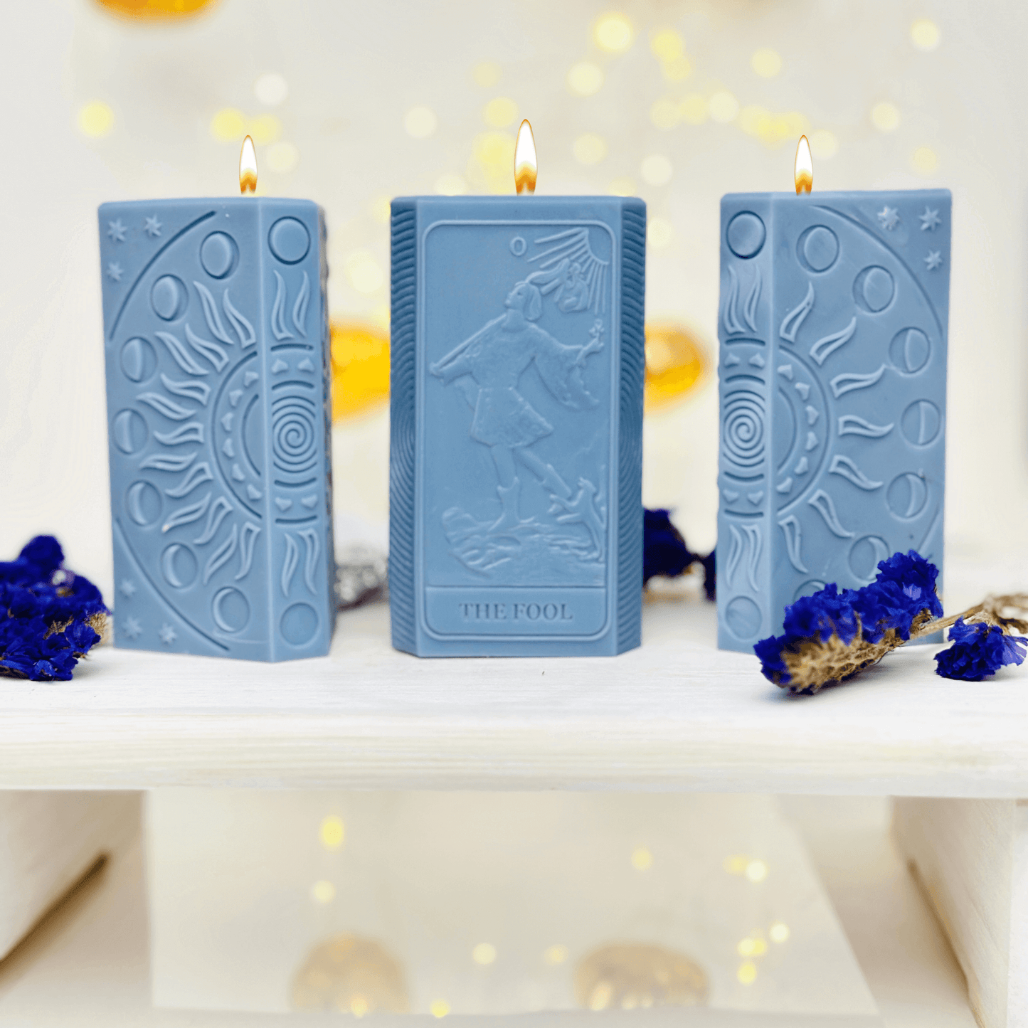 Three blue candles featuring The Fool tarot card and moon phases design, perfect for spiritual and manifestation crafts.