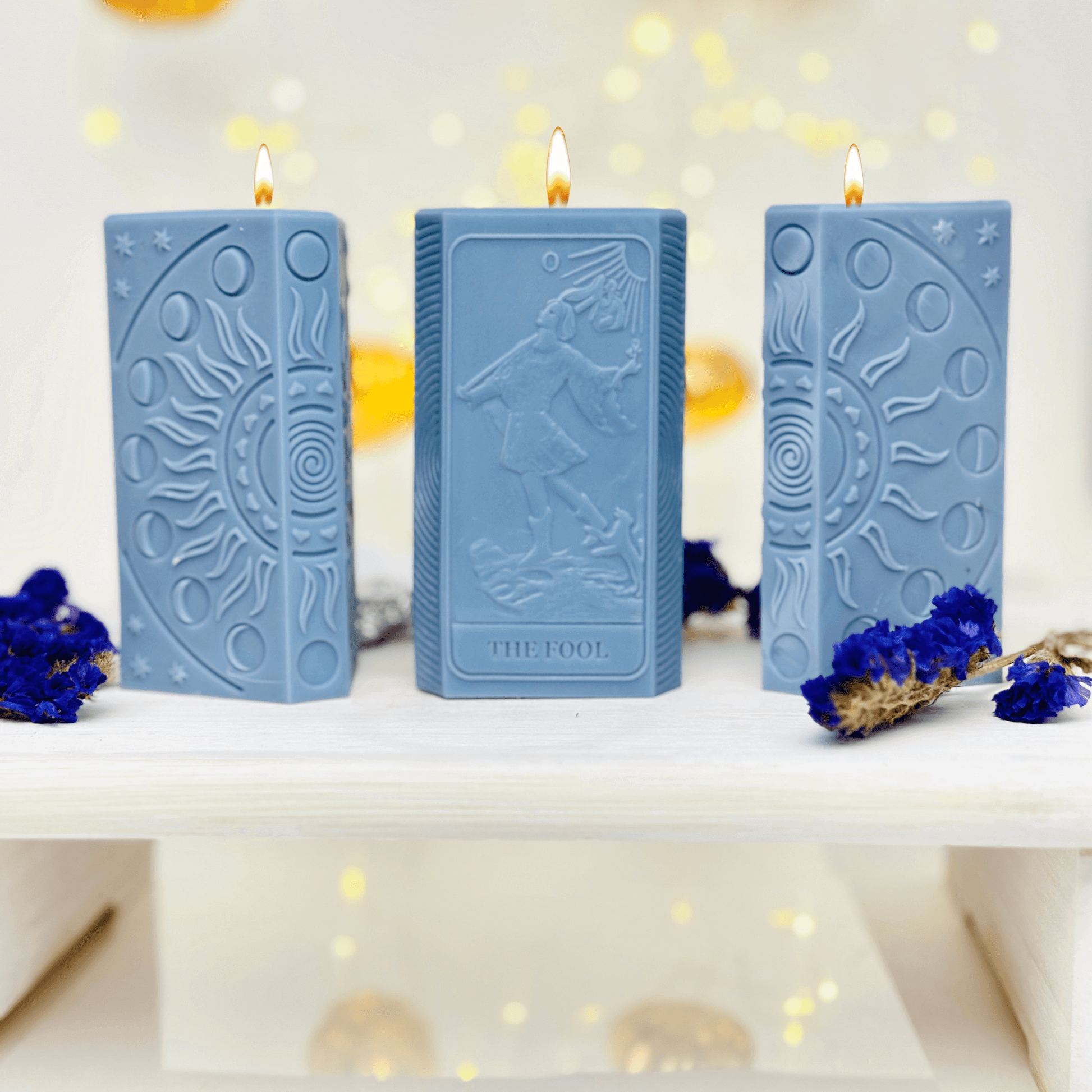 Three blue candles featuring The Fool tarot card and moon phases design, perfect for spiritual and manifestation crafts.