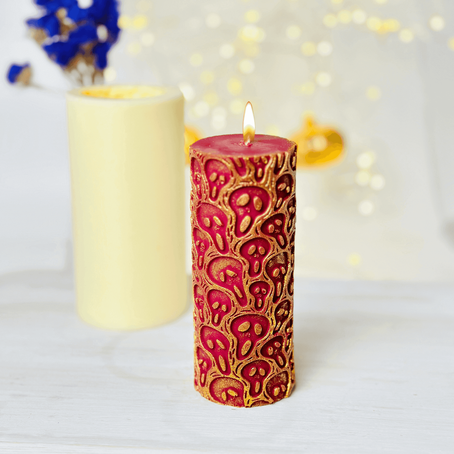 Vibrant red candle with ghost design, showcasing Halloween aesthetic, surrounded by a neutral-colored candle.
