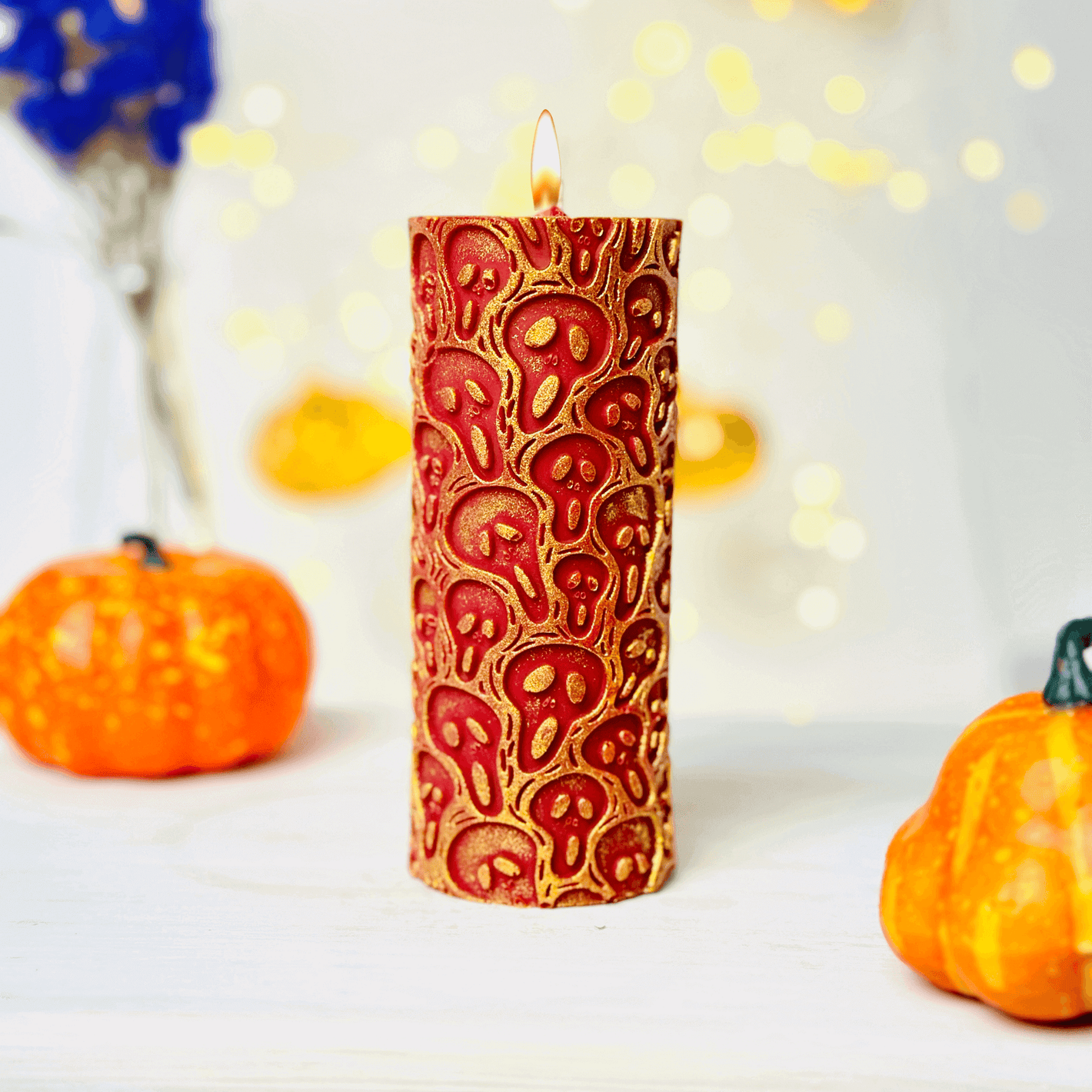 Halloween-themed candle with a spooky skull design, surrounded by orange pumpkins and festive decorations.