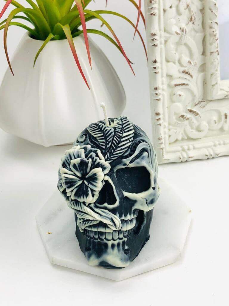 Gothic skull candle with floral designs on a marble base, perfect for Halloween decor.